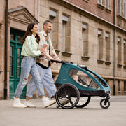 hauck Remolque de bicicleta y cochecito Dryk Duo Plus con suspensión, para 2 niños (6-48 meses), incluye barra de tiro, rueda de cochecito, bandera y luz LED, plegable, altura ajustable, maletero XL (verde oscuro)